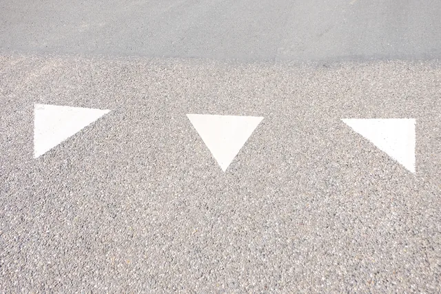 Haaientanden op het wegdek die aangeven dat je voorrang moet verlenen